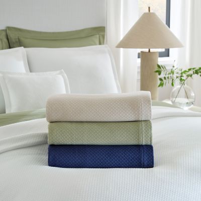 Rombo coverlet in white shown on the bed.
Stack: Top= Sand
            Middle= Willow
            Bottom=Navy
